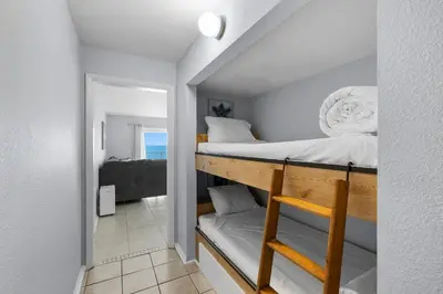 a small room with a bunk bed and a mirror at The Summit 606 in Panama City Beach
