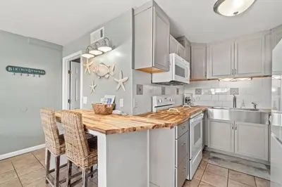 a kitchen with white cabinets and a wooden counter top at The Summit 105 in Panama City Beach