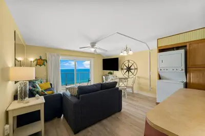 a living room with a couch and a kitchen with the ocean at The Summit 1116 in Panama City Beach