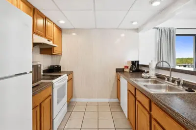 a kitchen with wooden cabinets and a white appliance at Moondrifter 608 in Panama City Beach