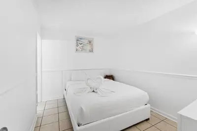 a white bedroom with a white bed with a bow on it at Moondrifter 608 in Panama City Beach