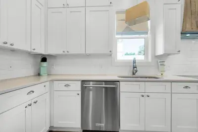 a kitchen with white cabinets and a stainless steel dishwasher at Aqua Blue in Inlet Beach