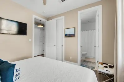a white bedroom with a bed and a bathroom at Aqua Blue in Inlet Beach