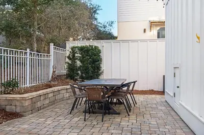 a table and chairs on a patio with a fence at Aqua Blue in Inlet Beach
