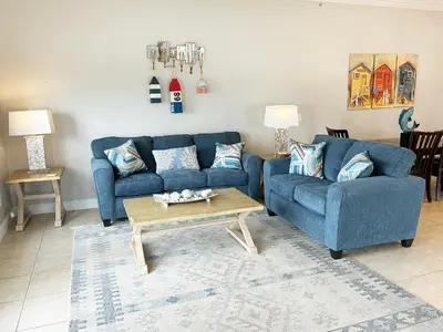 a living room with two blue couches and a coffee table at Vista del Mar I Ocean Overlook 302 in Panama City Beach