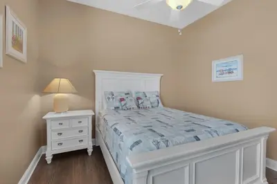a white bedroom with a bed and a night stand at Vista del Mar I Ocean Overlook 302 in Panama City Beach