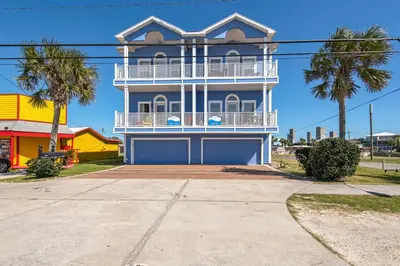 a blue and white house with palm trees in front of it at Vista del Mar I Ocean Overlook 302 in Panama City Beach