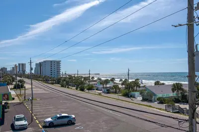 a street with cars parked on the side of a road with the ocean at Vista del Mar I Ocean Overlook 302 in Panama City Beach