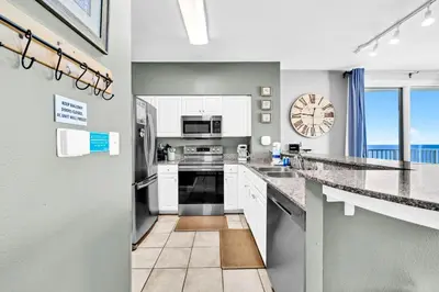 a kitchen with white appliances and a clock on the wall at Shores of Panama 1003 in Panama City Beach