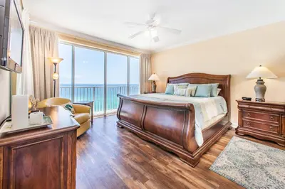 a bedroom with a bed and a balcony with the ocean at Boardwalk 1502 in Panama City Beach