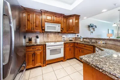 a kitchen with wooden cabinets and a stainless steel refrigerator at Boardwalk 1502 in Panama City Beach