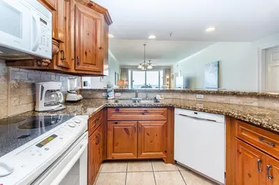 a kitchen with wooden cabinets and white appliances at Boardwalk 1502 in Panama City Beach