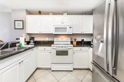 a white kitchen with white cabinets and a refrigerator at Tidewater 502 in Panama City Beach