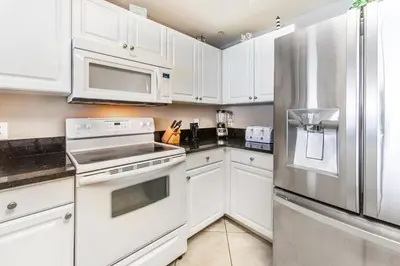 a kitchen with white cabinets and a stainless steel refrigerator at Tidewater 502 in Panama City Beach