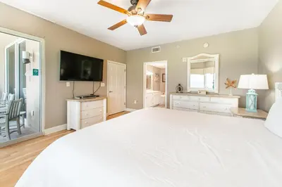 a large bedroom with a white bed and a flat screen tv at Tidewater 502 in Panama City Beach