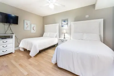 a bedroom with two beds and a flat screen tv at Tidewater 502 in Panama City Beach