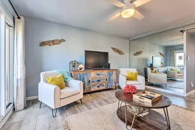 a living room with two chairs and a flat screen tv at PCB Beachfront Coastal Abode at Pinnacle Port! in Panama City Beach