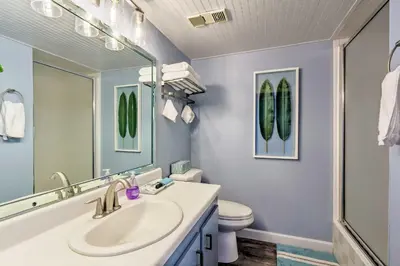 a bathroom with a sink and a toilet and a mirror at PCB Beachfront Coastal Abode at Pinnacle Port! in Panama City Beach