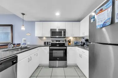a kitchen with white cabinets and a stainless steel refrigerator at Grand Panama 2-705 in Panama City Beach