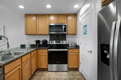 a kitchen with wooden cabinets and a black stove top oven at Sterling Breeze 2006 in Panama City Beach