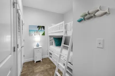 a white room with bunk beds and a lamp at Sterling Breeze 2006 in Panama City Beach