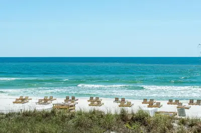 a group of chairs on a beach with the ocean at Ocean Villa 1406 in Panama City Beach