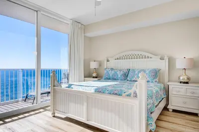 a white bedroom with a bed and a balcony at Tidewater 2115 in Panama City Beach