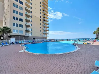 a swimming pool next to a building and the beach at Tidewater 2115 in Panama City Beach