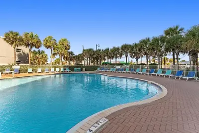 a large swimming pool with chairs and palm trees at Tidewater 2115 in Panama City Beach