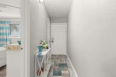 a hallway with a white door and a vase of flowers at The Summit 228 in Panama City Beach