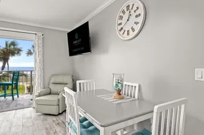 a dining room with a table and a clock on the wall at The Summit 228 in Panama City Beach