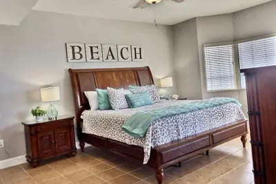a bedroom with a bed and a sign that reads beach at Happy Ours 2200 sq ft corner beachfront sleeps 12 in Panama City Beach