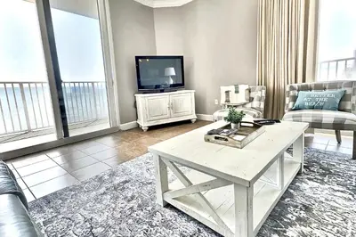 a living room with a table and a tv at Happy Ours 2200 sq ft corner beachfront sleeps 12 in Panama City Beach
