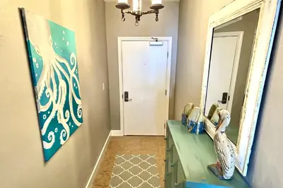 a hallway with a mirror and two statues on a counter at Happy Ours 2200 sq ft corner beachfront sleeps 12 in Panama City Beach