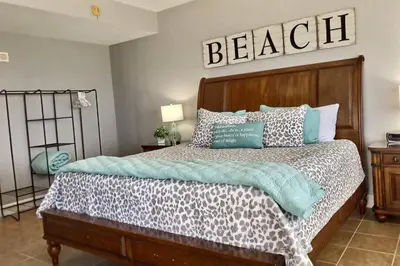 a bedroom with a bed with a sign on the wall at Happy Ours 2200 sq ft corner beachfront sleeps 12 in Panama City Beach