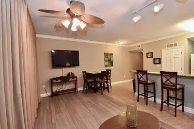a living room with a ceiling fan and a dining room at Amazing Sunset Oceanfront Condo in Panama City Beach