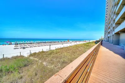 a boardwalk next to a beach with a building at Amazing Sunset Oceanfront Condo in Panama City Beach