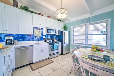 a kitchen with white cabinets and a table with a tableablish at Walk to Beach PCB Retreat with Private Pool! in Panama City Beach