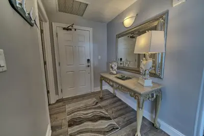 a hallway with a table with a lamp and a mirror at Calming Beachfront Condo with Oversized Balcony Facing the Gulf - Unit 2101 in Panama City Beach
