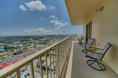 a balcony with two chairs and a view of a city at Calming Beachfront Condo with Oversized Balcony Facing the Gulf - Unit 2101 in Panama City Beach
