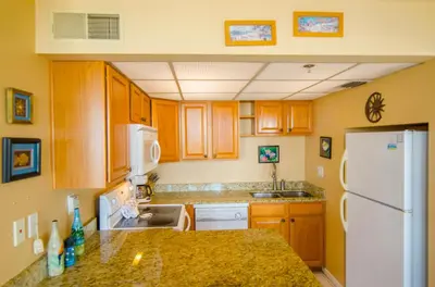 a kitchen with wooden cabinets and a white refrigerator at Sunbird 0208W 'Surfside Sandcastle' in Panama City Beach