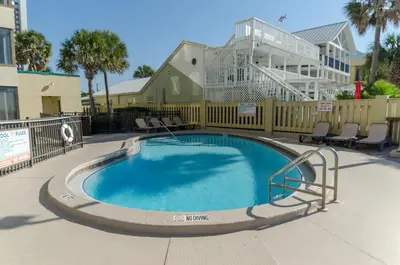 a swimming pool with chairs and a building in the background at Sunbird 0208W 'Surfside Sandcastle' in Panama City Beach