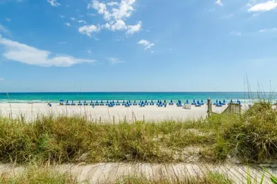 a beach with a lot of chairs and the ocean at Sunbird 0208E 'Dolphin Watch' in Panama City Beach