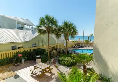 an apartment patio with a pool and palm trees at Sunbird 0208E 'Dolphin Watch' in Panama City Beach