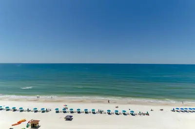 a beach with chairs and umbrellas and the ocean at Edgewater 2-0104 'Sandcastle Dreams' in Panama City Beach