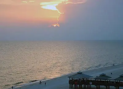 a beach with a pier and the ocean at sunset at Sunbird 0908W 'Captain's Cove' in Panama City Beach