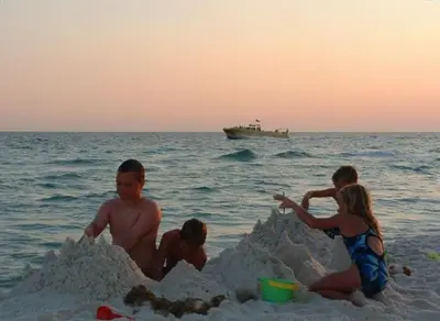 a group of people playing in a sand castle on the beach at Sunbird 0908W 'Captain's Cove' in Panama City Beach