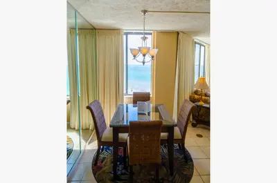 a dining room with a table and chairs and a window at Sunbird 0908W 'Captain's Cove' in Panama City Beach