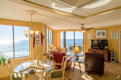a living room with a table and chairs at Sunbird 1008W 'Hugo's Sugar Shack' in Panama City Beach