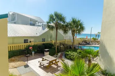 a patio with a picnic table and a pool at Sunbird 1008W 'Hugo's Sugar Shack' in Panama City Beach